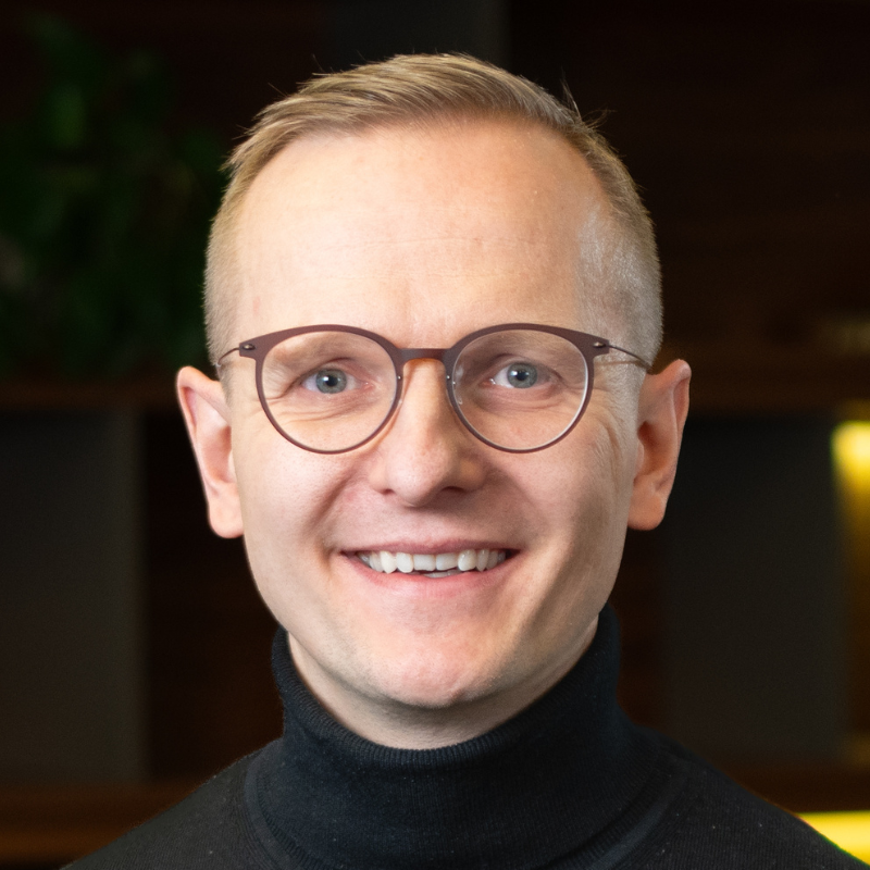 Ein lächelnder blonder Mann mit Brille.