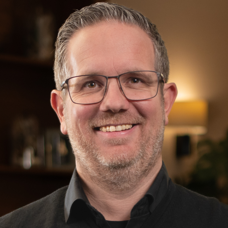 Ein lächelnder Mann mit Brille.