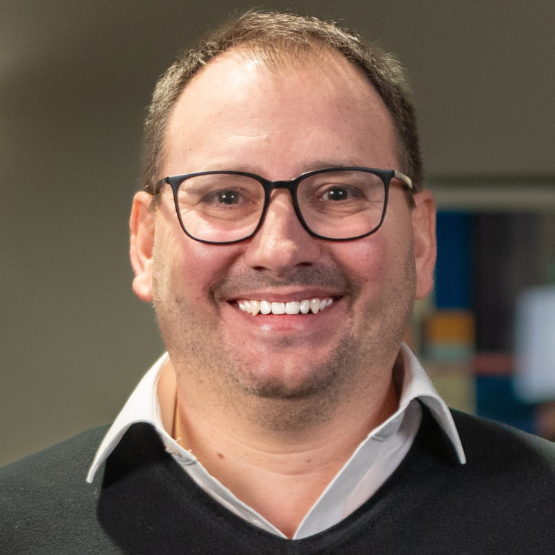 Ein lächelnder Mann mit Brille.