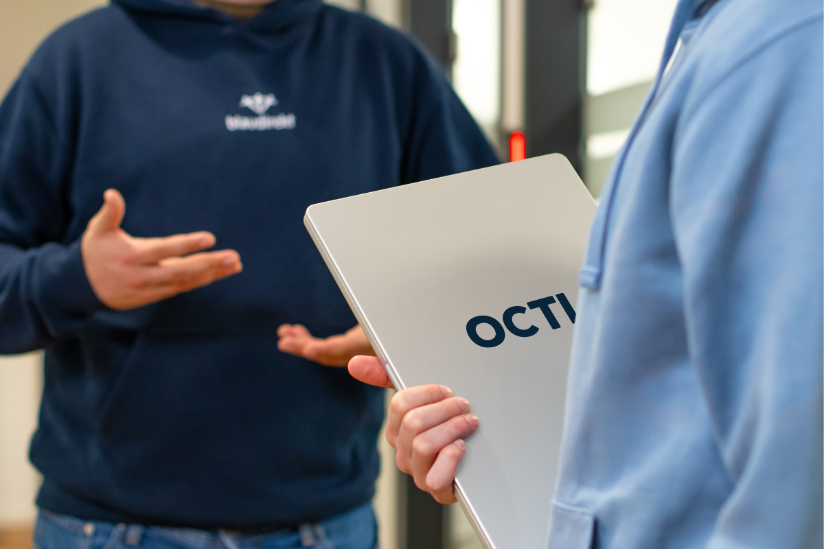 Eine Person hält einen Laptop in der Hand mit der Beschriftung 'OCTI'.